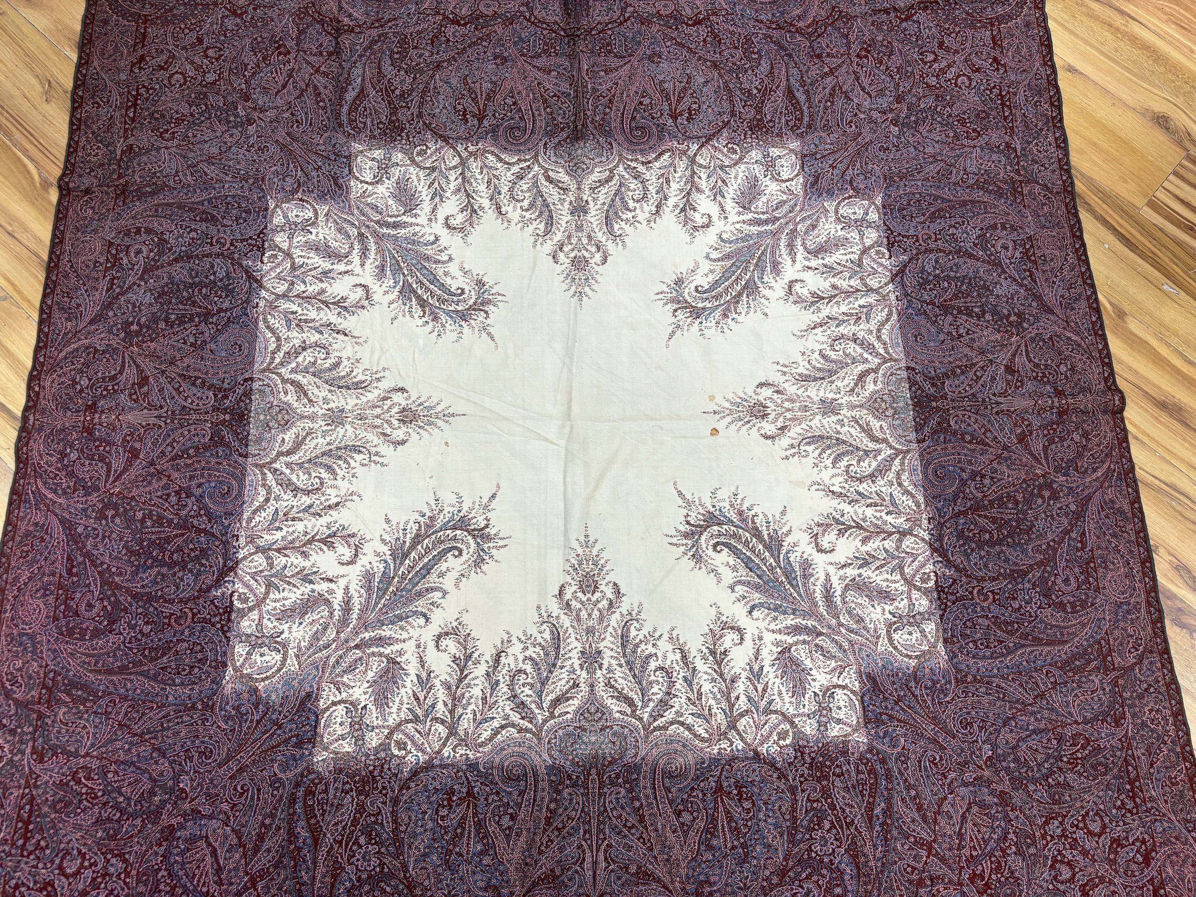 A late 19th century wool woven Paisley shawl with cream central cartouche (some damage)